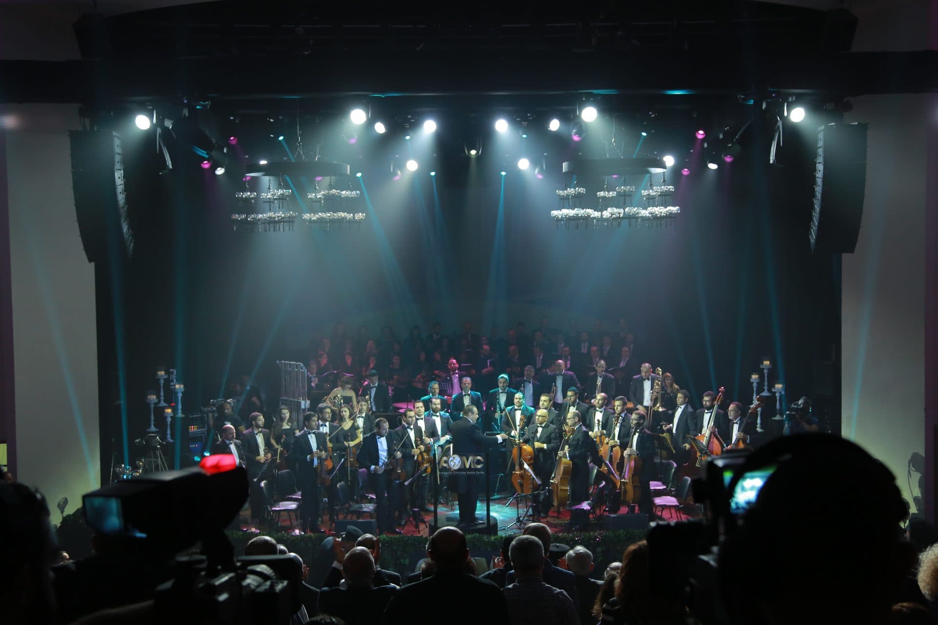 A speaker at the podium surrounded by the orchestra