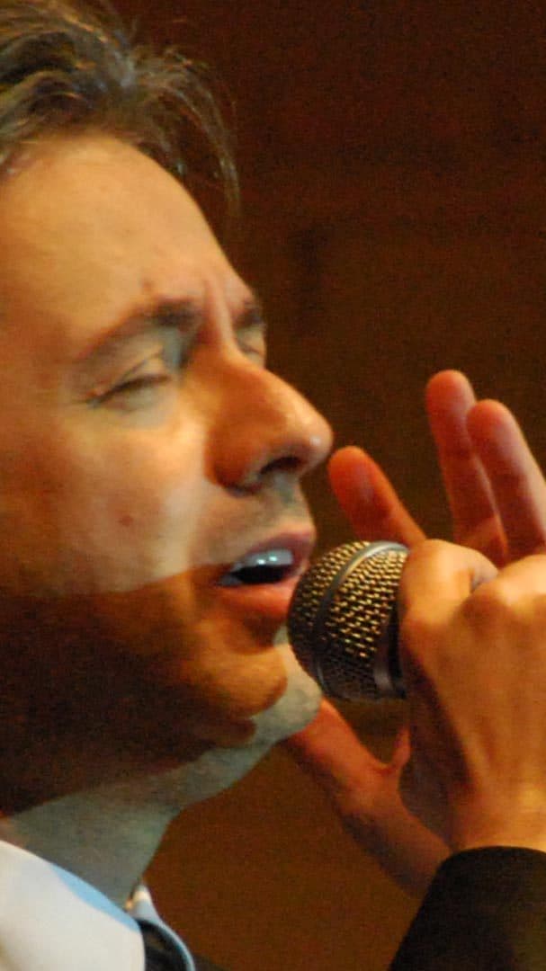 Marwan Khoury singing on a stage of white columns in pink light
