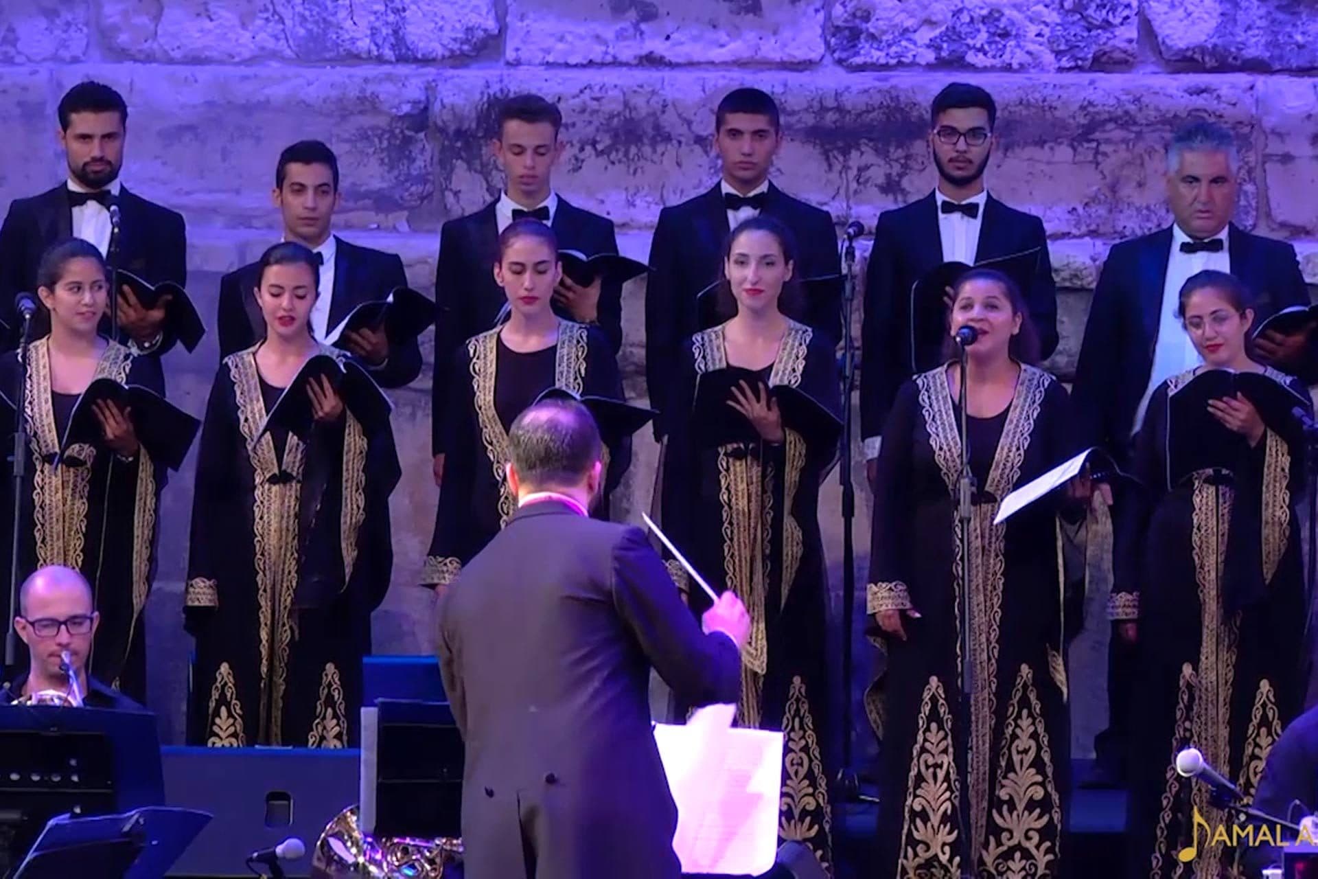The conductor leading the choir in front of the orchestra