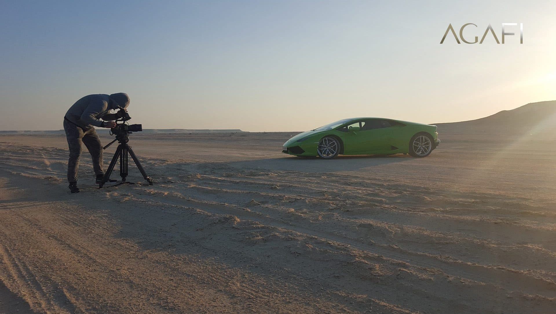 A camera on a tripod facing the Lamborghini at sunrise