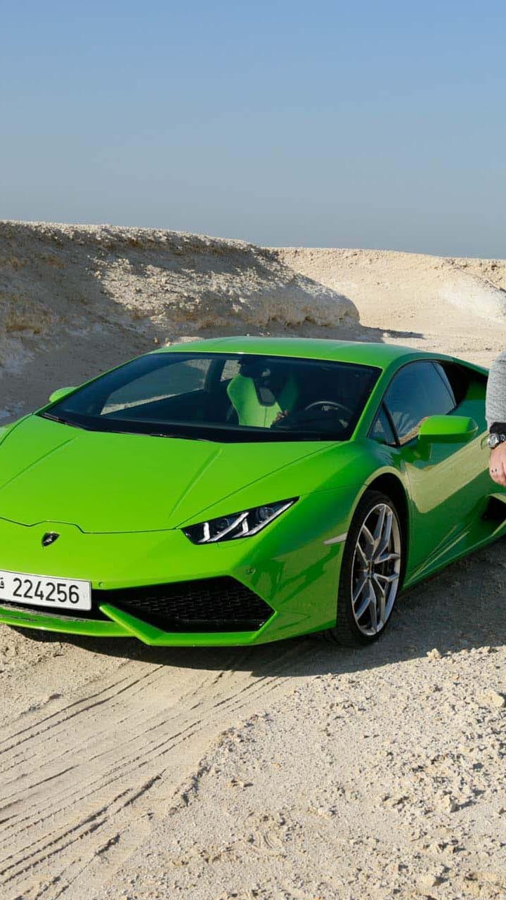 A green Lamborghini Huracán in the Qatar desert at sunset