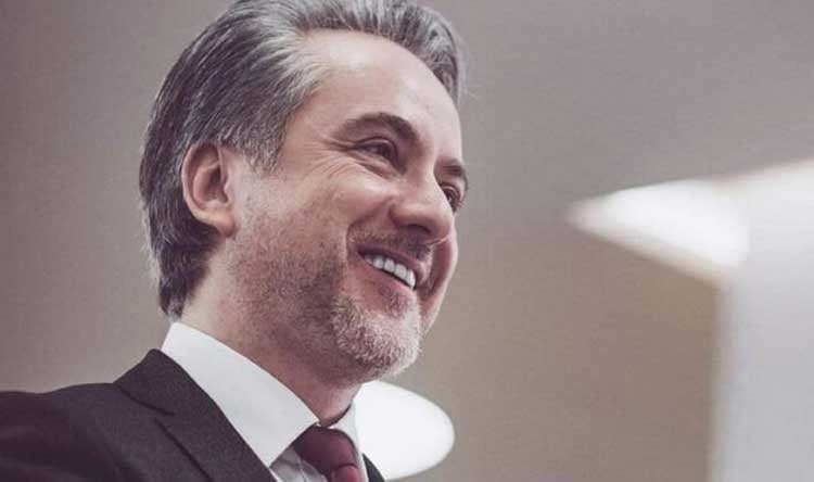 A singer smiling, in a dark suit