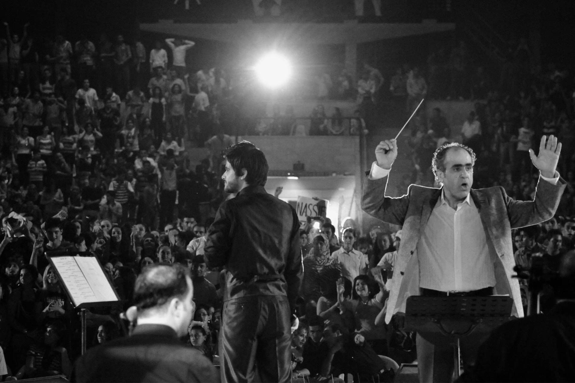 A conductor in front of a full open-air crowd