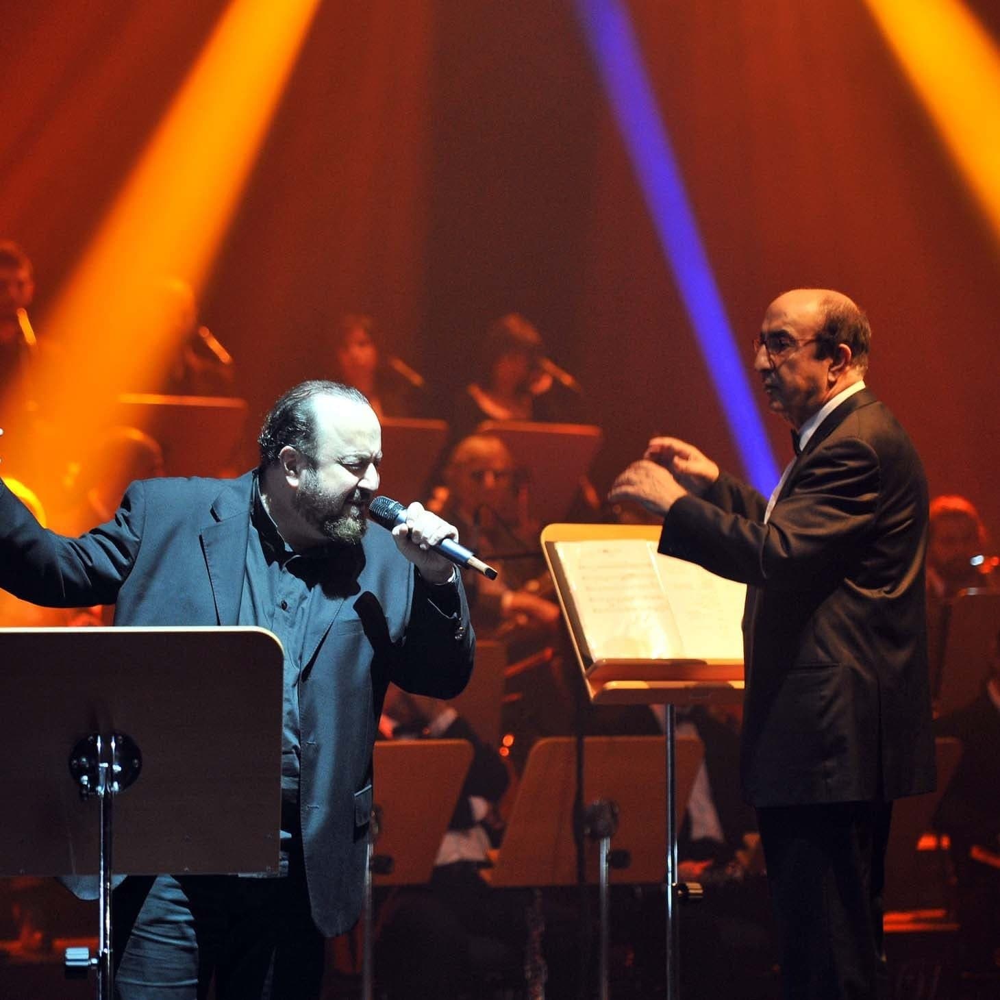 A singer and a conductor in front of the orchestra