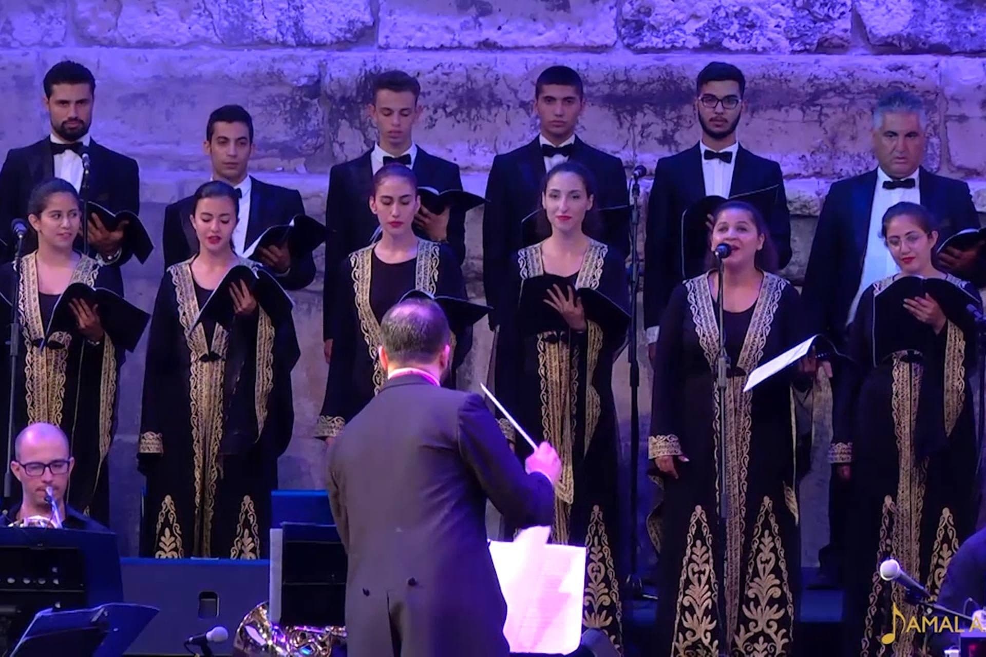 A choir in embroidered robes in front of a stone wall