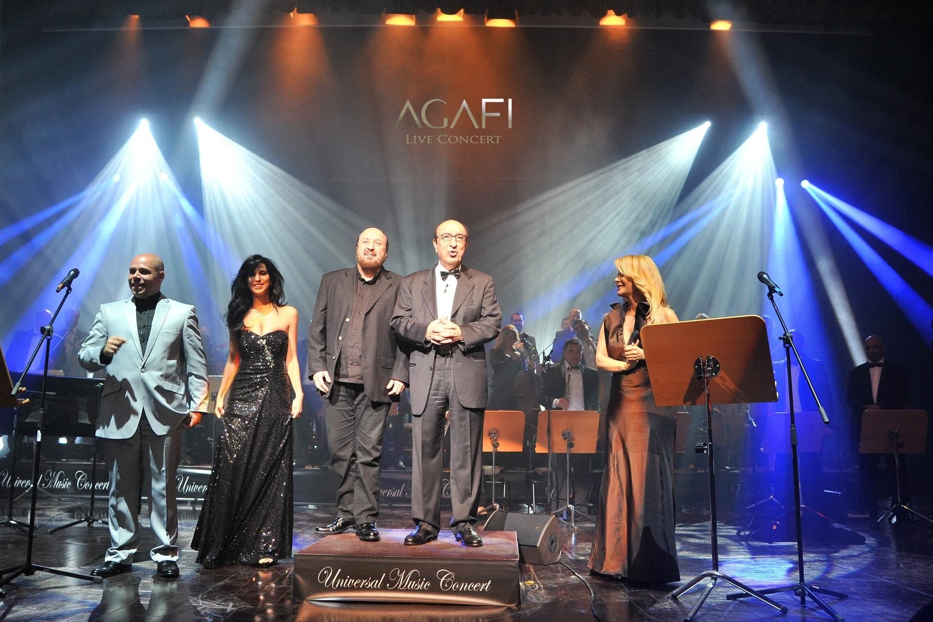 Singers and musicians under blue beams at the Universal Music Concert